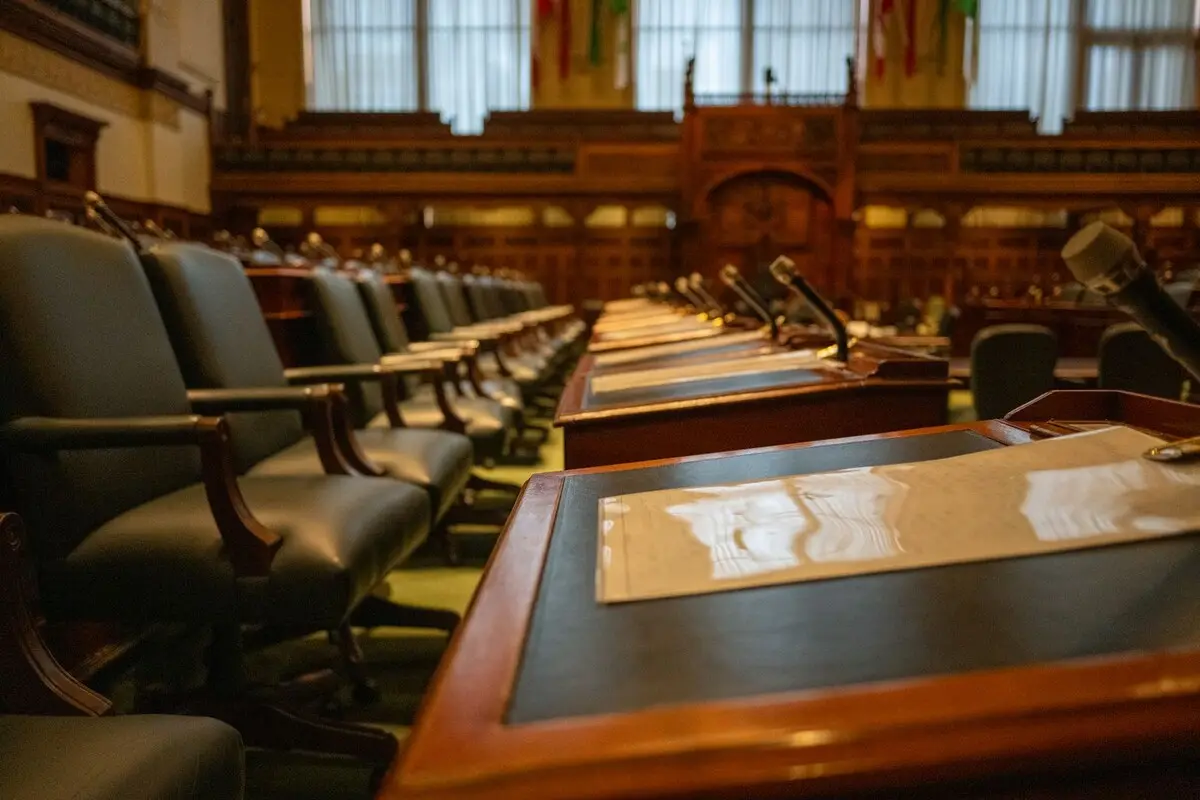 An empty legislative chamber with rows of desks and microphones