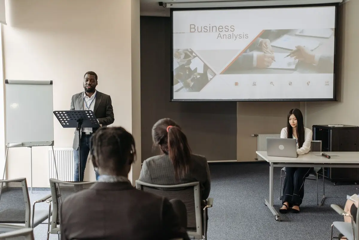 A presenter leading a business training session for a seated professional audience
